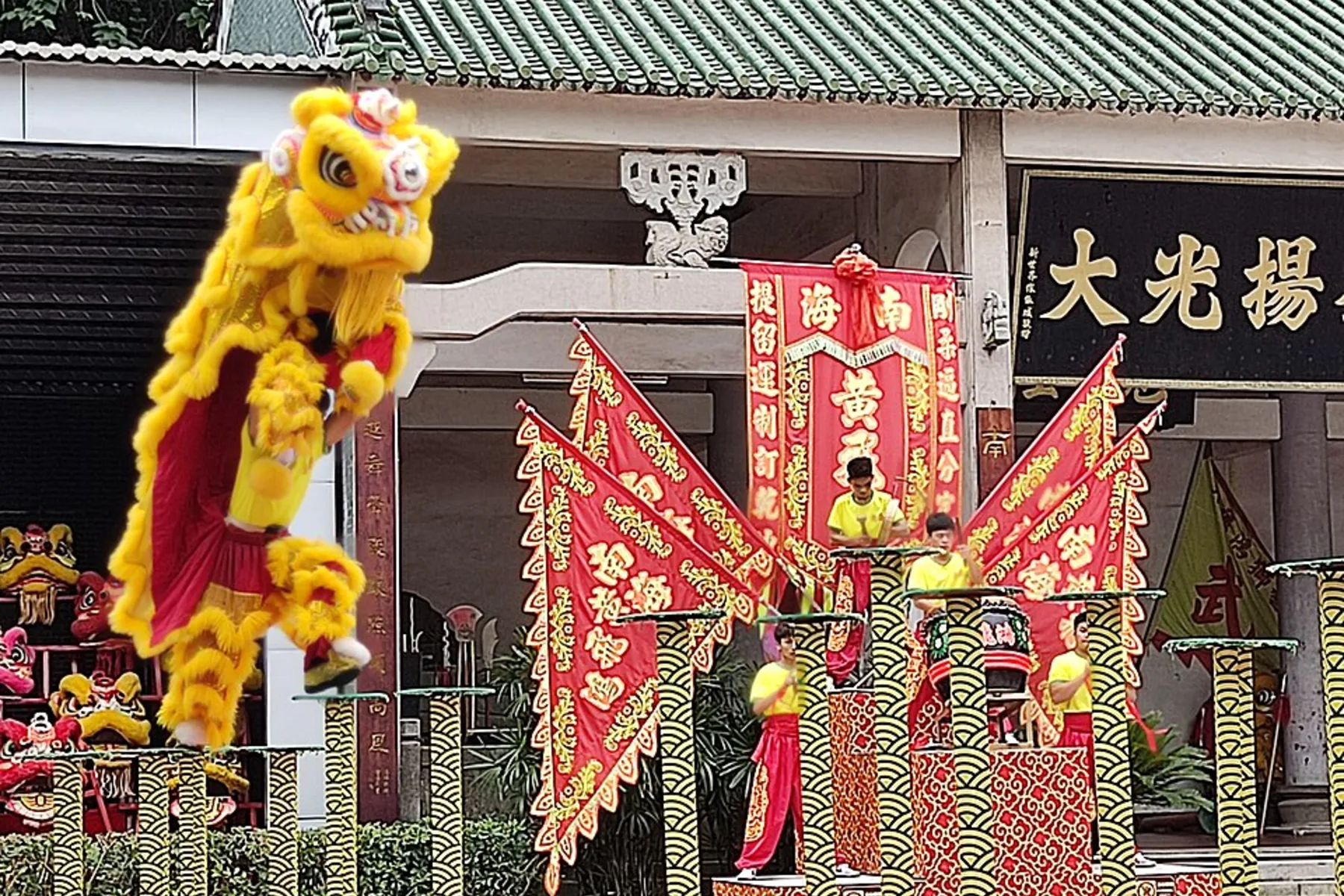 Yellow lion-dance performer jumping between high poles at the Wong Fei-hung Lion Dance and Martial Arts School in Xiqiao